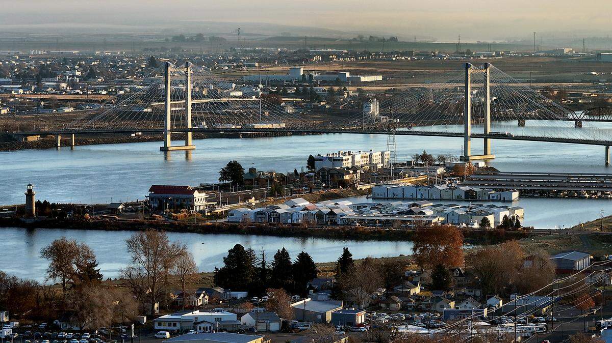 Drone view of the cable bridge over the Columbia River showing Port of Kennewick’s Clover Island, lighthouse and boat houses with Pasco in the background including Local Bounty.