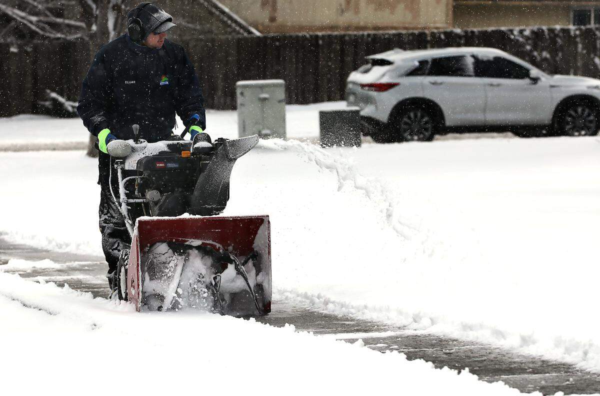 Kennewick city employee Elijah Torres deploys a snow blower Friday morning to clear a fresh layer of overnight snow from the sidewalks around the Highlands Grange Park at 1600 S. Union St. in Kennewick.