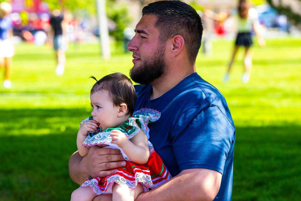 Anthony Reisch, of Richland, holds his 9-month-old daughter Viviana while watching the Pasco Cinco de Mayo parade from the shade on Saturday in downtown Pasco.