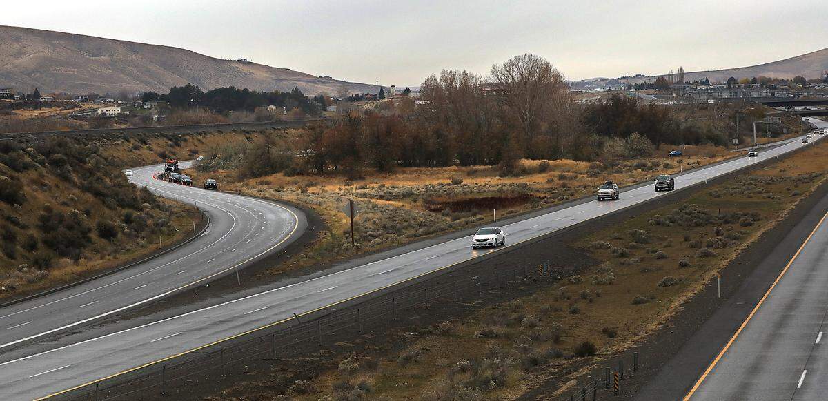 Traffic streams past on I-182, as investigators from the Washington State Patrol document the scene were a person was found dead in the median of eastbound Highway 240 to Interstate 182 in Richland.