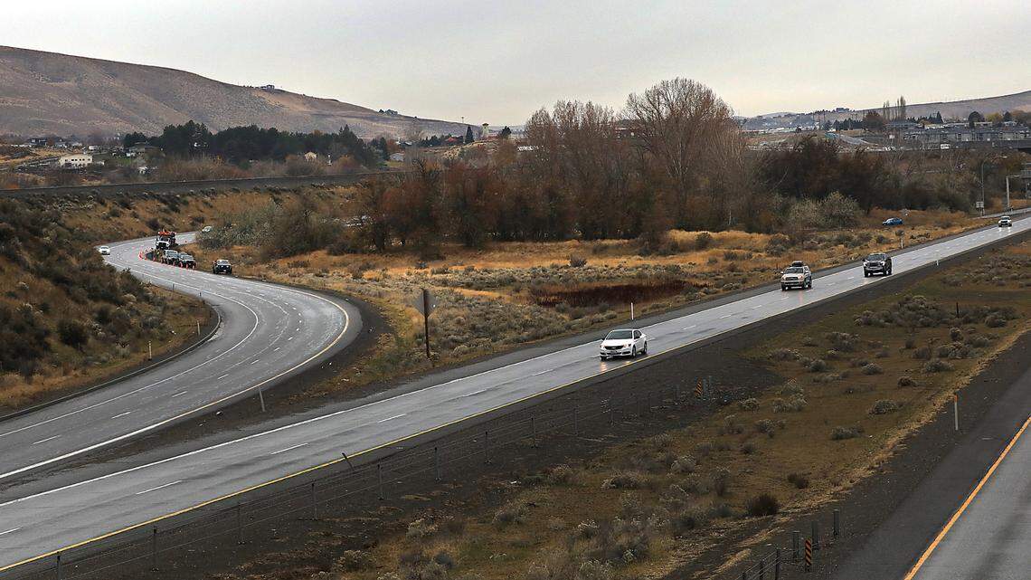 Traffic streams past on I-182, as investigators from the Washington State Patrol document the scene were a person was found dead in the median near Richland.