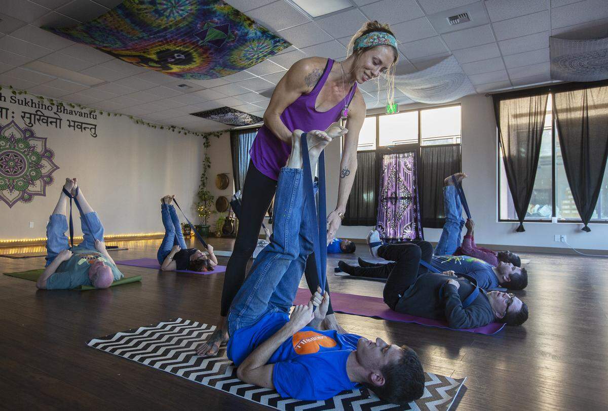 The Lotus Pad yoga instructor Cecelia Owczarski helps Mike McCloud stretch his legs with a yoga strap inside her studio in Kennewick.