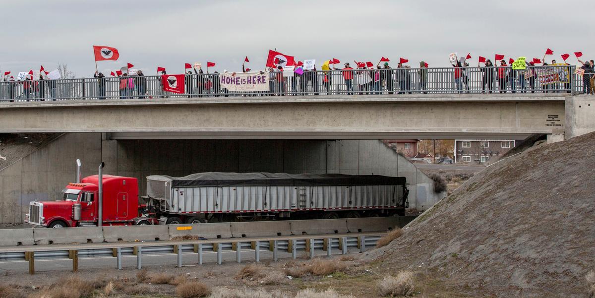 A sign stating “Home is Here” is draped over the railing of the walking bridge that spans Highway 395 along West Court Street in Pasco. About 50 United Farm Workers members marched in Pasco, joining a nationwide call for immigration reform through a local “Day Without Immigrants” rally.