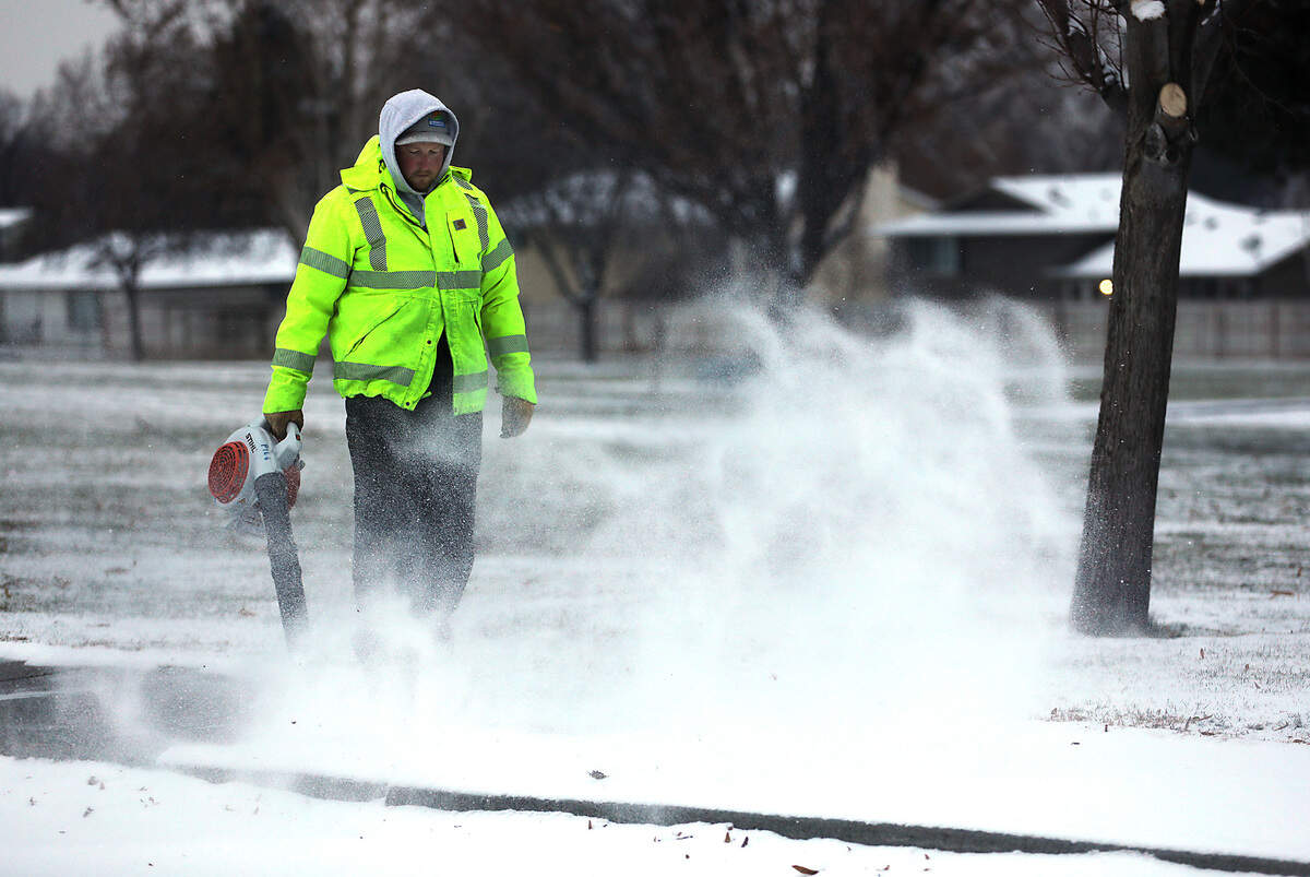 Thomas Workman, an employee for the city of Kennewick, uses a leaf blower to clear snow from sidewalks in the Highlands Grange Park off South Union Street in Kennewick. Overnight snowfall measured less than an inch in most places.