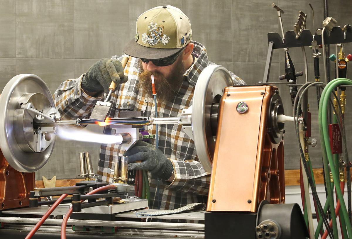 CJ Freestone, lead artist at Prohibition Studios, shapes a glass tube mounted in a lathe at the new studio and gallery in downtown Kennewick. His mouthpiece is connected to the heated glass tube and is used to help shape it. The public grand opening is Nov. 30. See story on Page 2A. Watch a video at: tricityherald.com/video