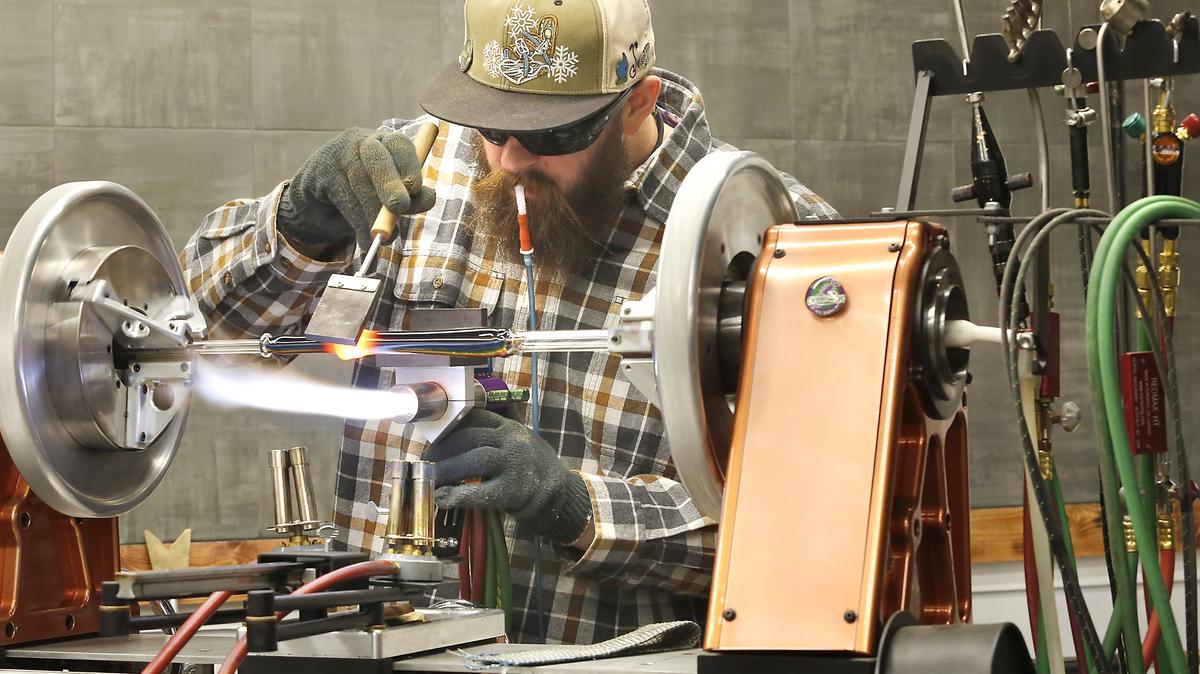 CJ Freestone, lead artist at Prohibition Studios, shapes a glass tube mounted in a lathe at the new studio and gallery in downtown Kennewick. His mouthpiece is connected to the heated glass tube and is used to help shape it. The public grand opening is Nov. 30. See story on Page 2A. Watch a video at: tricityherald.com/video
