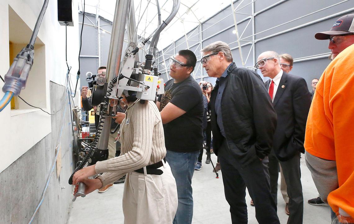 Energy Secretary Rick Perry looks over the shoulder of Chiawana High STEM student Geovanni Beltran as he manipulates a remote-operated arm Tuesday at the contamination-free mock-up of Hanford’s 324 Building in Richland.