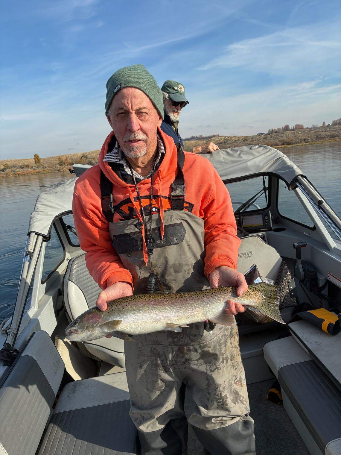 Dennis Dauble holds up a surprise hatchery steelhead while Ted Poston ponders his luck on from the bow of the boat.