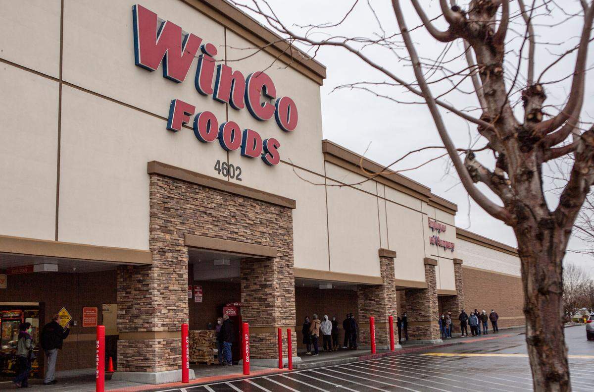 People wait to shop at WinCo Foods in Kennewick on Monday morning. On Sunday, Gov. Jay Inslee announced a statewide lockdown will go into effect this week to address the growing number of COVID-19 cases across the state and nation.