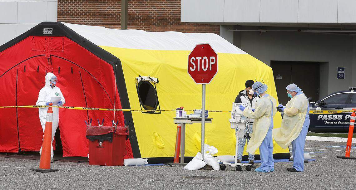 Medical workers dressed in protective equipment at Lourdes Health pre-screen a man for signs or symptoms of the coronavirus at a tent set up in the emergency room parking lot of the Pasco hospital.