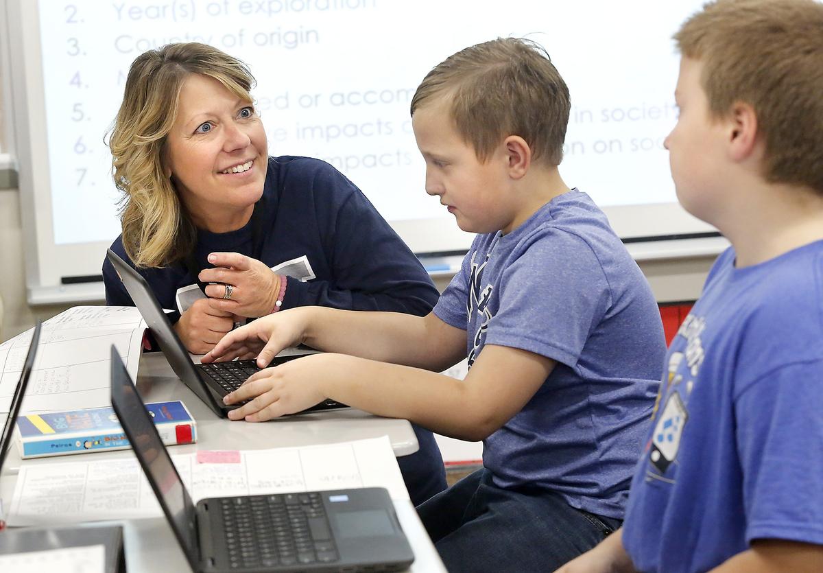 Fifth-grade teacher Tami Simundson works with Wiley Elementary students Cooper Dorsett, middle, and Trenton Klein during a technology assignment to create an infographic about an explorer using their Chromebook. The Richland School District is incorporating technology with traditional subjects to help kids innovate and create. Watch a video at: tricityherald.com/video