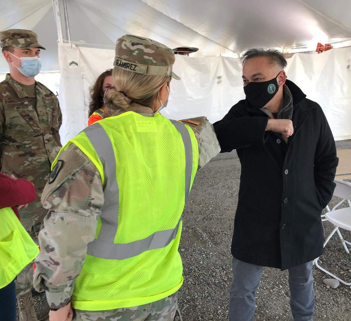 Dr. Umair Shah, the Washington state secretary, bumps elbows with a member of the Washington state National Guard during a tour of the Benton County Fairgrounds COVID vaccination clinic in Kennewick.