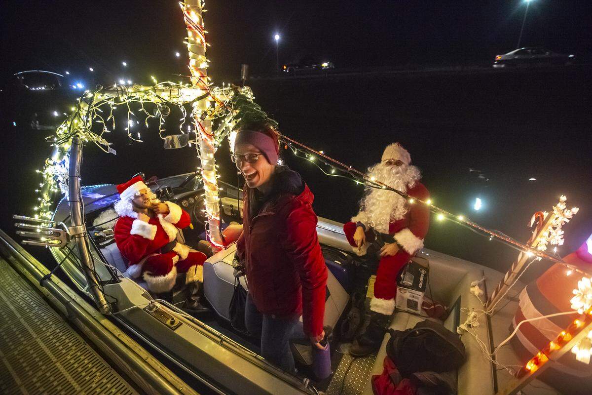 Friends Evan Halladay, left, fixes his Santa Claus beard Friday as Felicia Dumont gets into the boat and Tony Irusta relaxes before leaving the dock at Clover Island Marina for the Christmas lighted boat parade starting at the cable bridge in Kennewick. 
