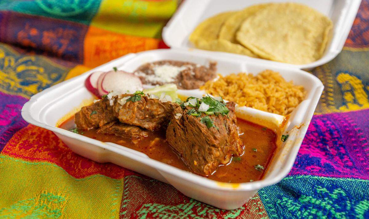 Traditional birria in consume with refried beans, rice and homemade corn tortillas from Picante Mexican Taqueria food truck.