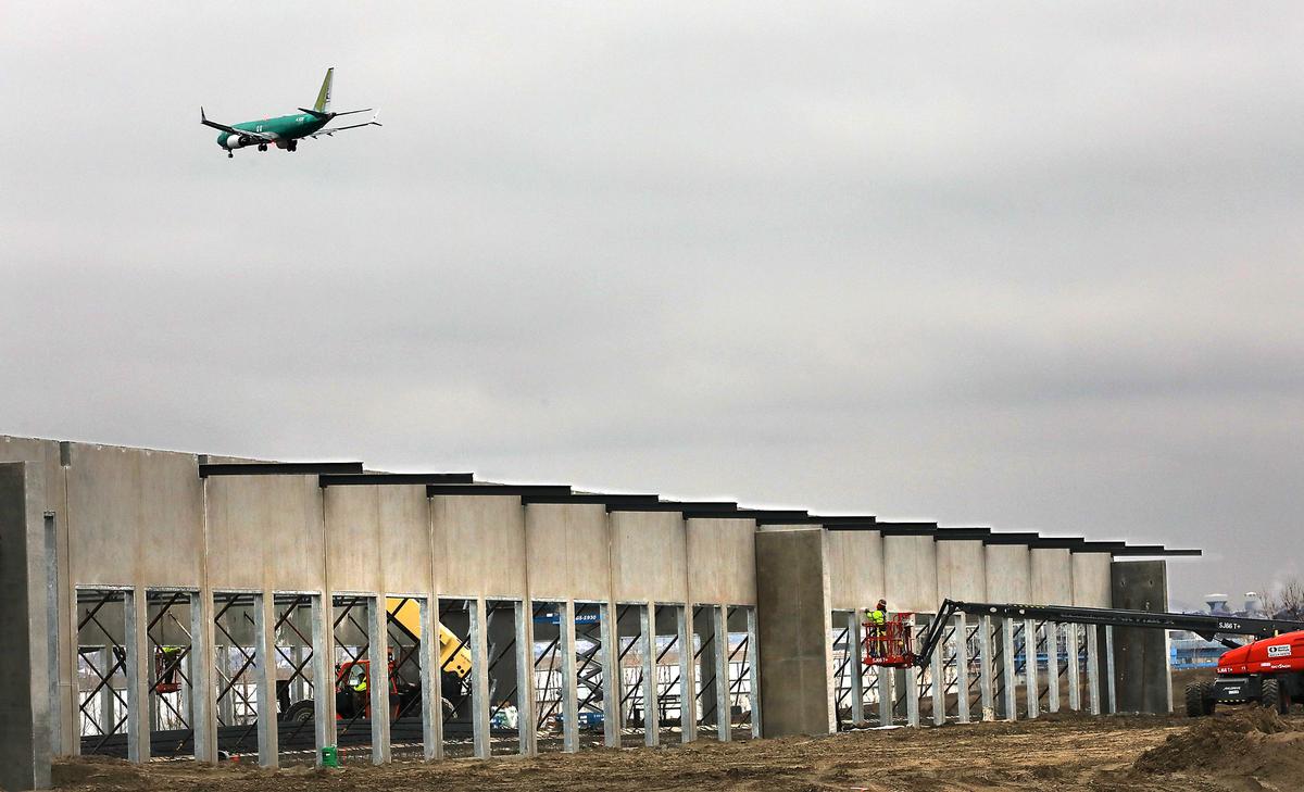 Construction crews work from boom lifts on the new Old Dominion Trucking facility on North Capital Avenue as a passenger jet prepares to land at the nearby Tri-Cities Airport in Pasco.