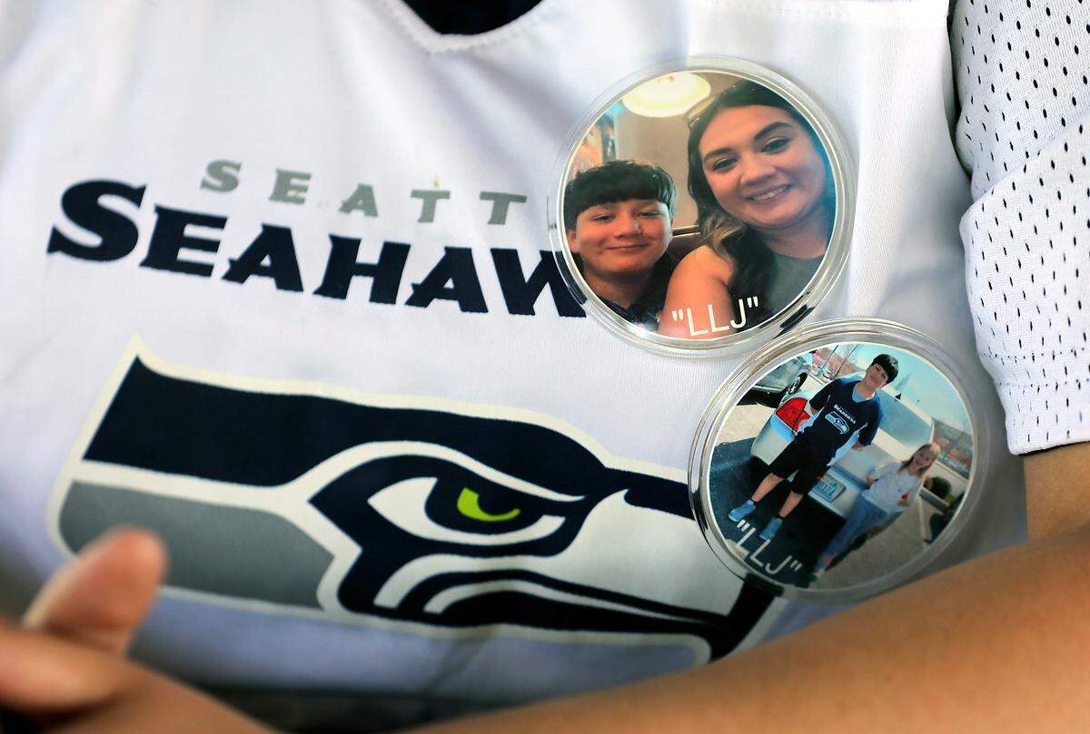 Sandra Ramirez wears buttons honoring her son, Joseph Martinez, while wearing his flag football jersey recently at the Columbia Point Marina Park in Richland. 