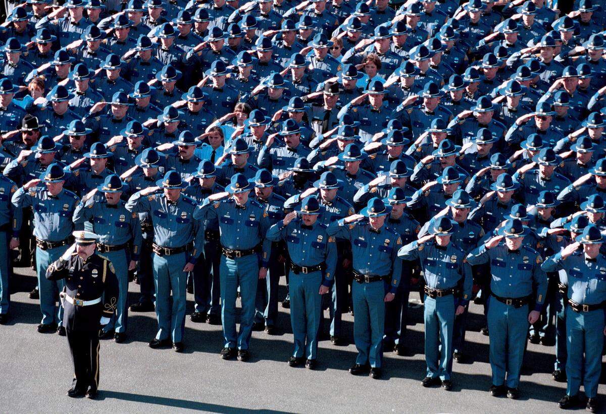 Members of the Washington State Patrol salute as the family of slain trooper James E. Saunders arrive in Kennewick for his memorial service in October 1999.
