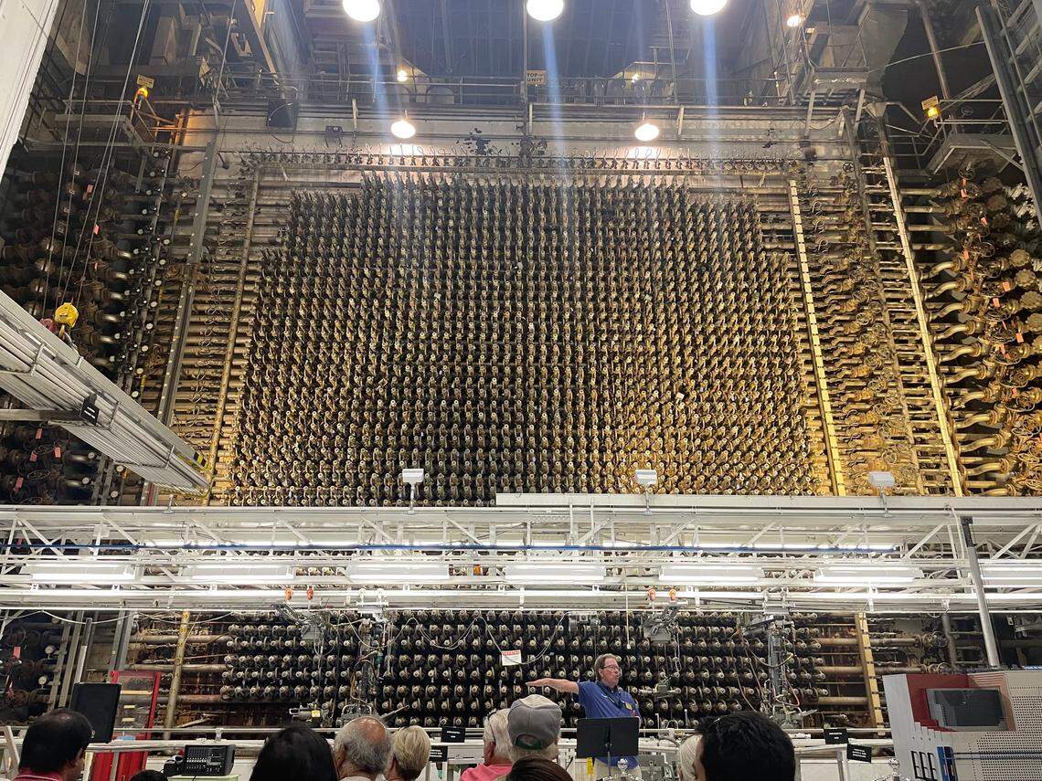 National Park Service visitors to Hanford’s B Reactor sit in front of the towering front face of the Eastern Washington reactor while hearing about its role in launching the Atomic Age.