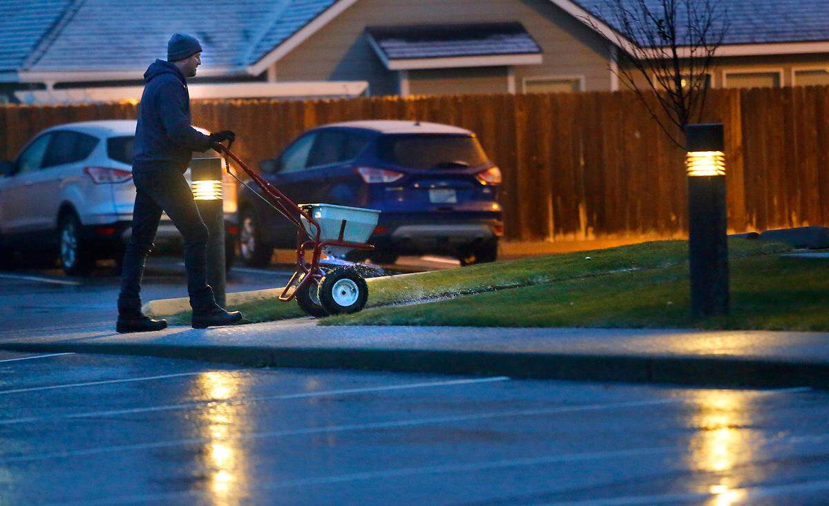 Dallas DeCoria, owner of ABV of Kennewick, works in Wednesday’s predawn darkness spreading ice melt on a crunchy frozen wintry mix coating the parking lot and walkways of an office building on West 24th Avenue in Kennewick. An overnight mix of freezing rain and sleet around the Mid-Columbia region created slick spots, causing several crashes on highways and roads. No serious injuries were reported.