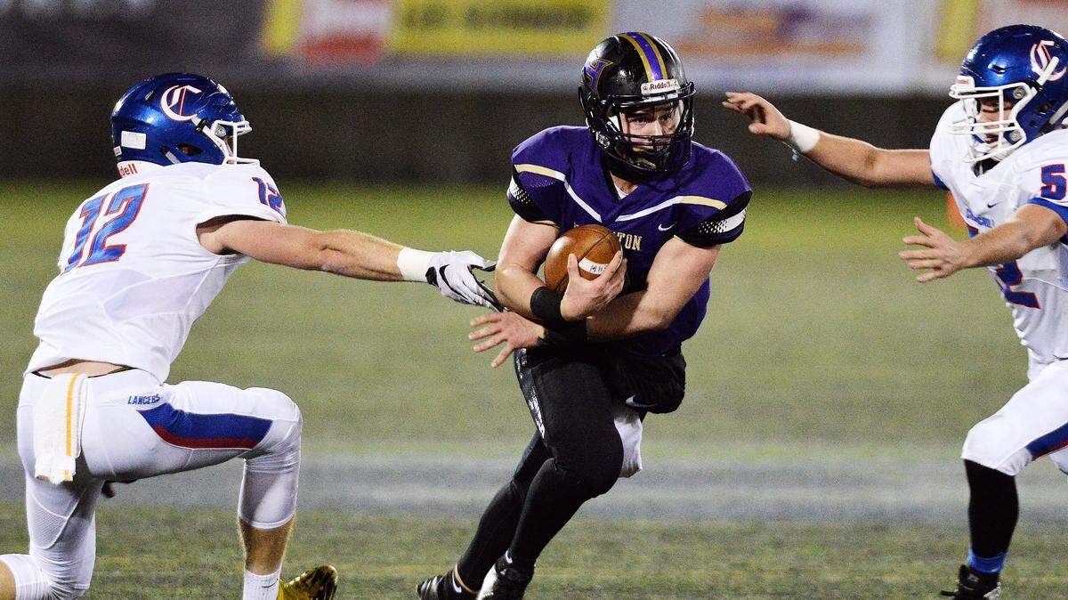Hermiston quarterback Andrew James splits Churchill defenders Jax Arnold (12) and Kannon Ruano during the Bulldogs’ 38-35 win over the Lancers in the Oregon Class 5A state championship game in November.