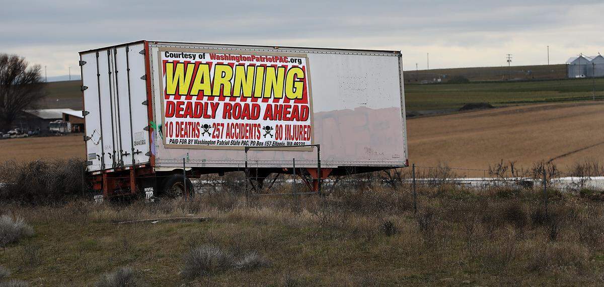 A large billboard attached to a semi-trailer in a field near Sagemoor Road about 16 miles north of Pasco warns southbound drivers of the deadly and dangerous stretch of highway created by cross roads. 