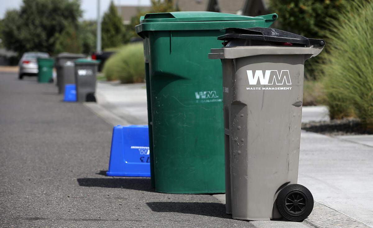 Waste Management garbage cans and recycle bins sit near the curb in a residential area of Kennewick. 