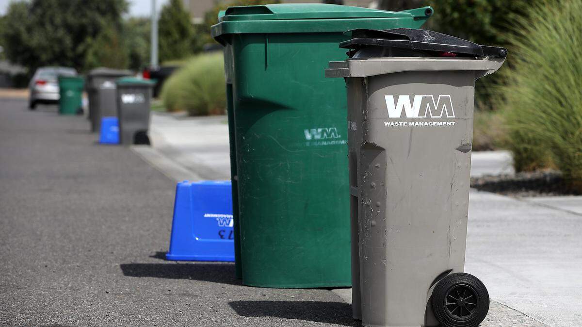 Waste Management garbage cans and recycle bins sit near the curb in a residential area of Kennewick. Price increases and substantial changes in services may be in store for Kennewick residents according to ongoing negotiations between Kennewick city government and Waste Management. The two parties’ current 10-year contract is set to expire on Dec. 31 this year.