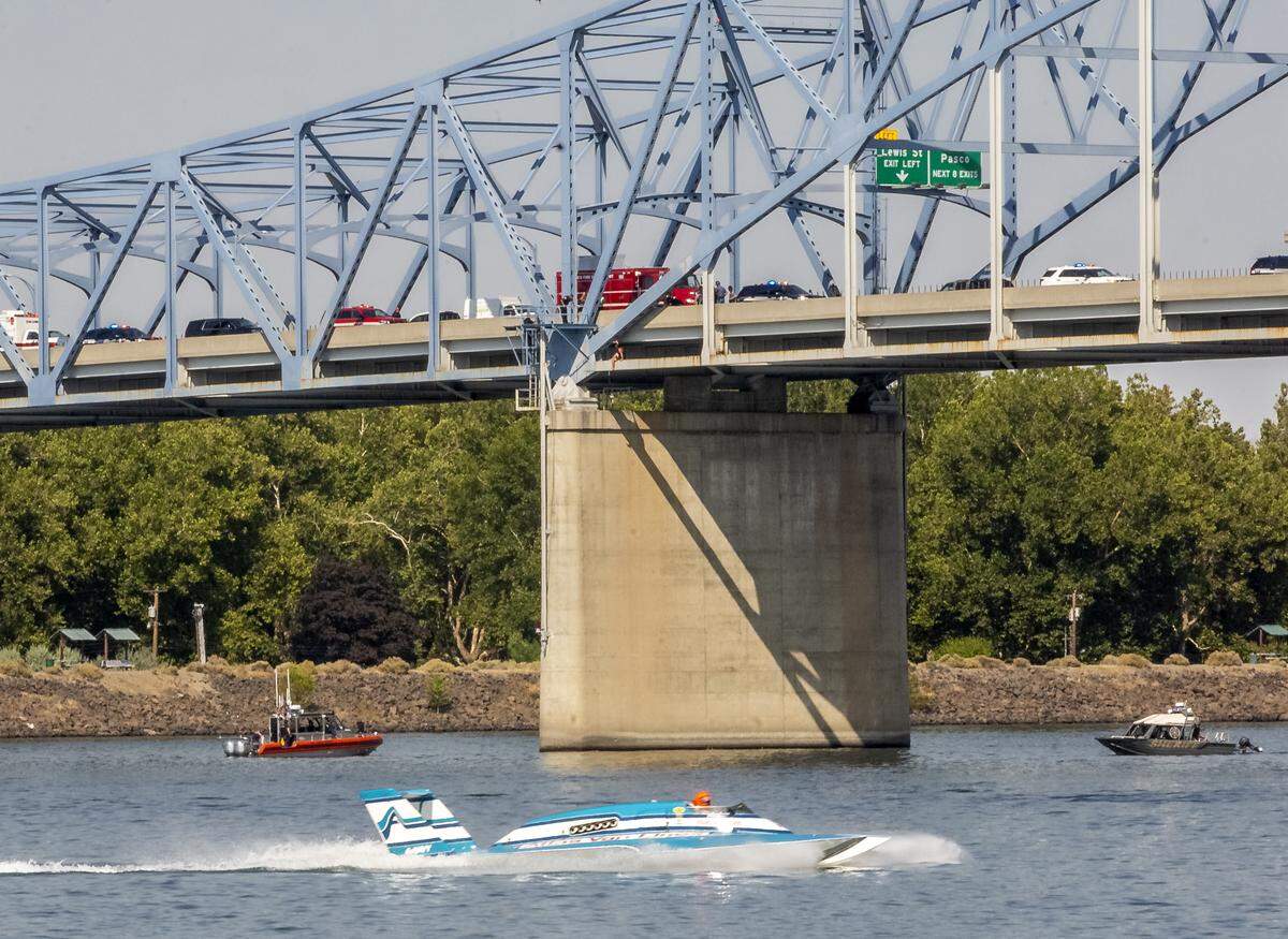 Officers attempt to rescue a woman who is sitting on the under structue of the blue bridge on Friday during Water Follies. The races were halted until she was rescued.