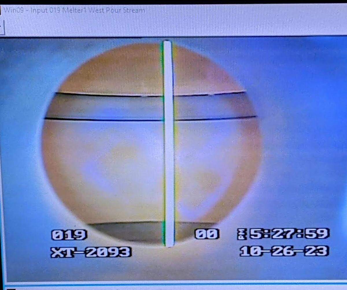 A monitor shows a stream of molten glass being poured.