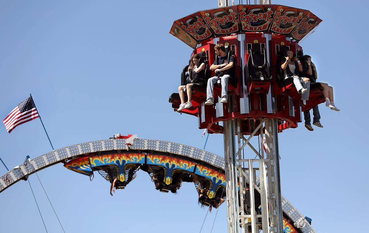 Riders on the Extreme Scream anticipate reaching their drop point as riders on the the Fireball hangsupside down Friday afternoon in the Davis Shows Northwest carnival area at the Benton Franklin Fair & Rodeo in Kennewick.