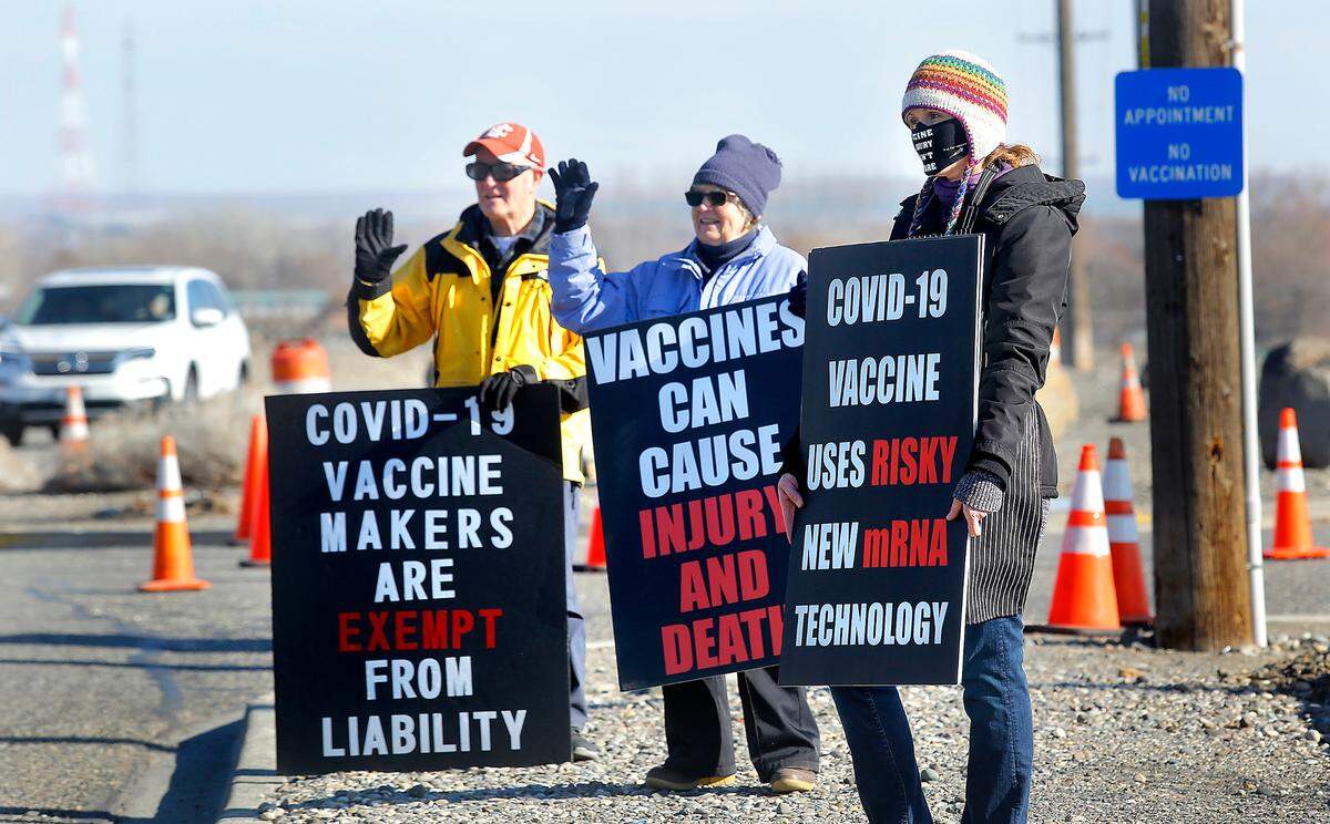 Local members of Informed Choice Washington hold picket signs Wednesday afternoon with anti-vaccination messages near the entrance to the drive-thru COVID-19 vaccination site at the Benton County Fairgrounds in Kennewick.