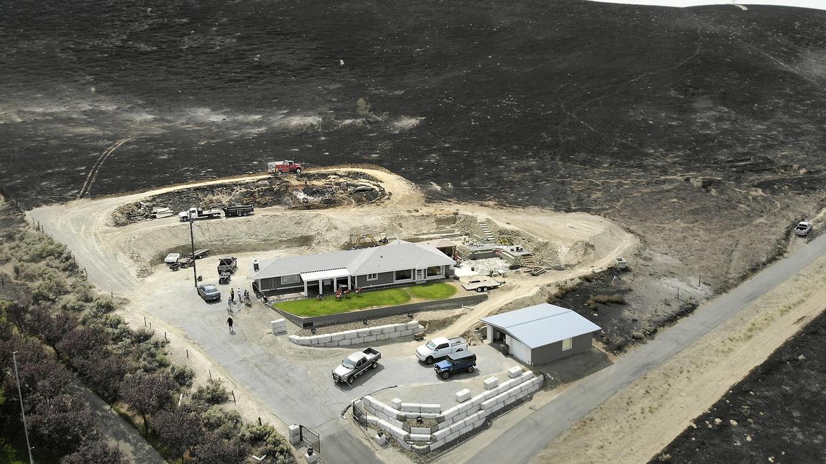 A fire truck monitors the charred landscape for hot spots Sunday afternoon behind a house at the end of South Ely Street in Kennewick. Fire officials say the 5,000-acre wildfire that roared into Kennewick and continued east into Benton County over the weekend is now considered contained.