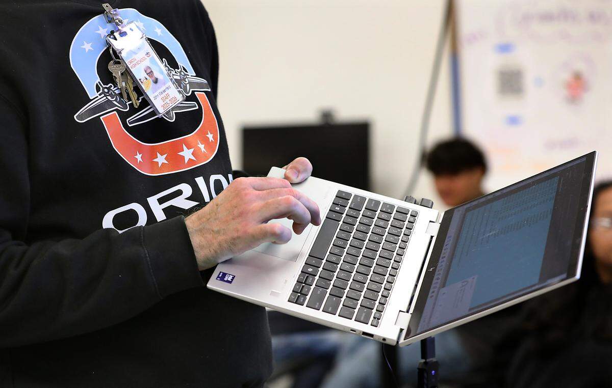 Orion High school John Weisenfeld holds his laptop while demonstrating the AI component students used to research their recent projects.