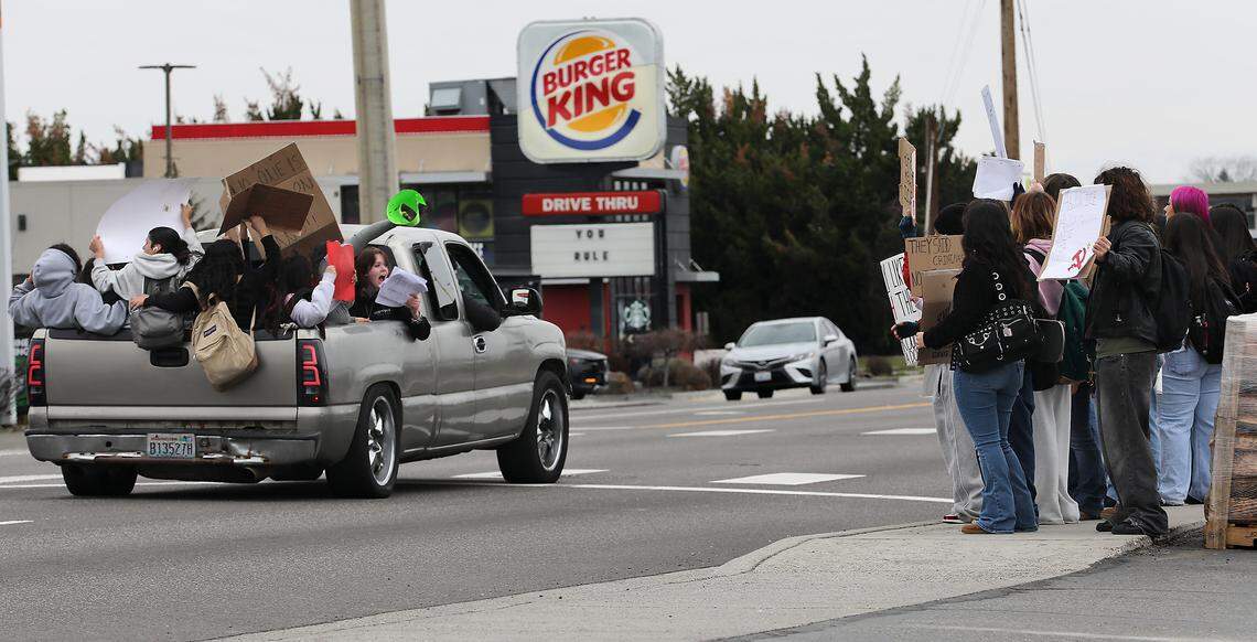 A pickup filled with high school students drives past others on the sidewalk headed eastbound on West Court Street near the highway overpass Friday afternoon during a protest march against Immigration & Customs Enforcement in Pasco.