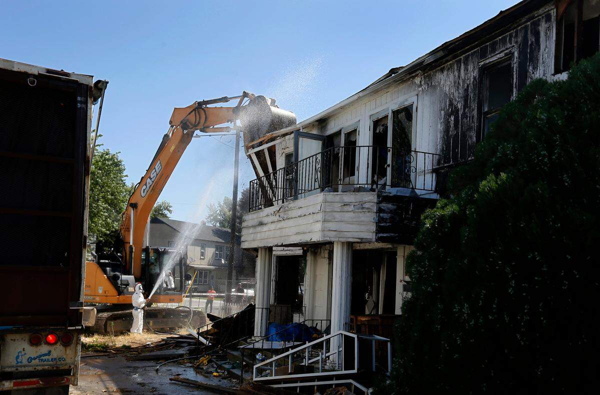 Workers from Big D’s Construction use respirators and wear protective coveralls as they start razing the house damaged by fire three years ago.