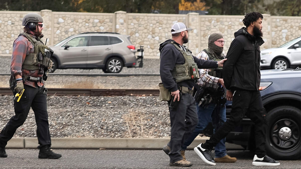 Law enforcement officers take Raymond Smith, 24, into custody Wednesday morning near Highway 240 and Duportail Street in Richland. 