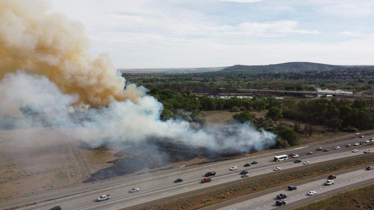 Smoldering brush flared up again near Columbia Point south of Interstate 182 near the twin bridges on Thursday as part of an 85-acre fire that started Wednesday near Highway 240.