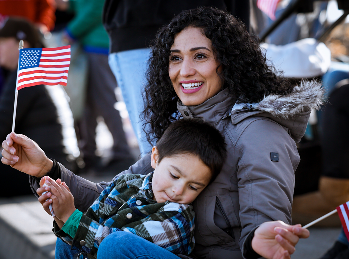 Lili Sanchez and her son, Quentin, wave American flags as parade participants pass along West Van Giesen Street during the 26th annual Veterans Day Parade in West Richland, Wash., on Saturday, Nov. 8, 2025.