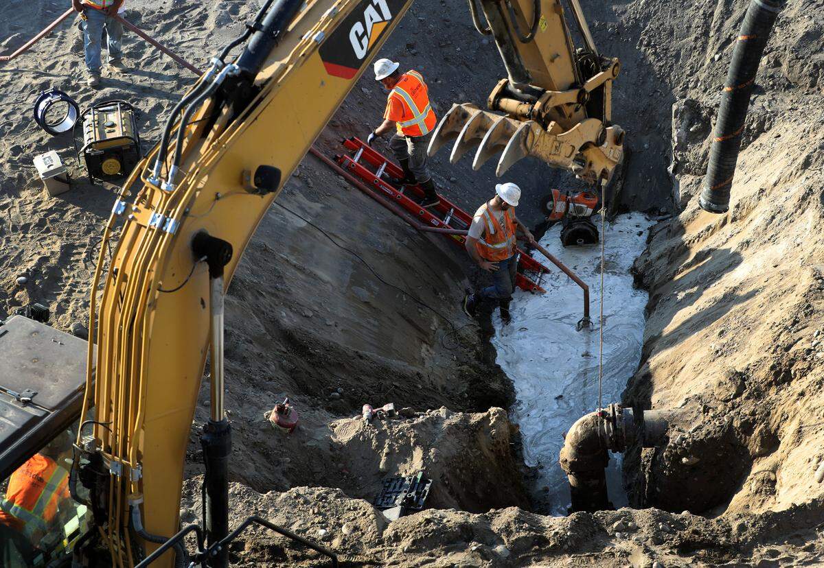 Crews pump out excess water prior to an excavator lifting out a section of old water main pipe early Thursday morning as part of the ongoing Lewis Street Overpass Project in Pasco.