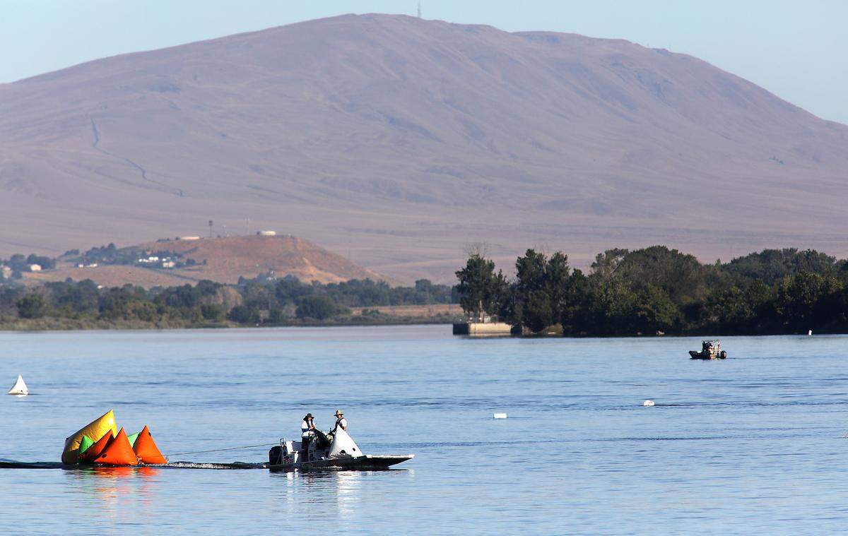 A Tri-Cities Water Follies rescue sled pulls inflatable race course markers across the Columbia River early Friday morning to outline the upriver turns of the 2.5 mile course for the unlimited hydroplanes. This layout of the course has been altered this year.