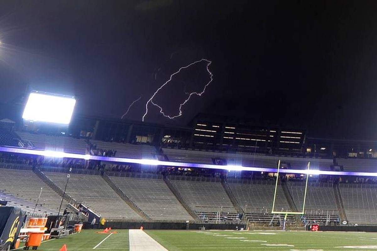 Lightning flashes in the sky beyond Husky Stadium during a weather delay in the first quarter of an NCAA college football game between Washington and California on Sept. 7.