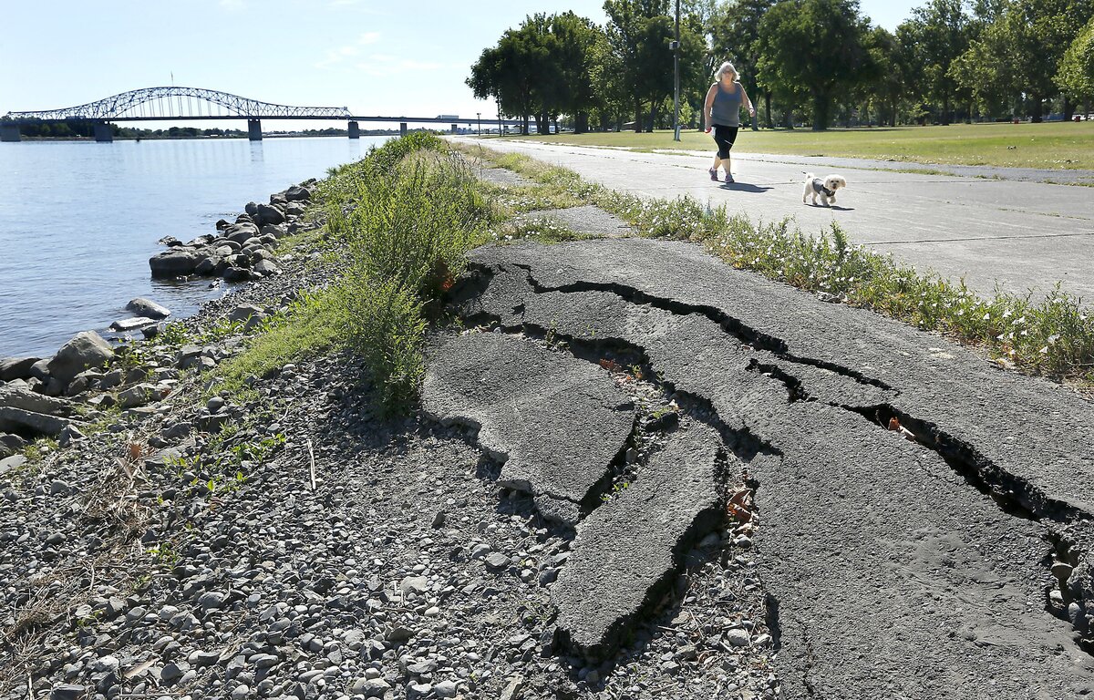Melanie Blatman of Kennewick and her dog, Uma, walk past a section of collapsed asphalt on the shoreline of the Columbia River in Kennewick's Columbia Park. Erosion from high water this spring may have undermined sections of the paved walkway in the park.