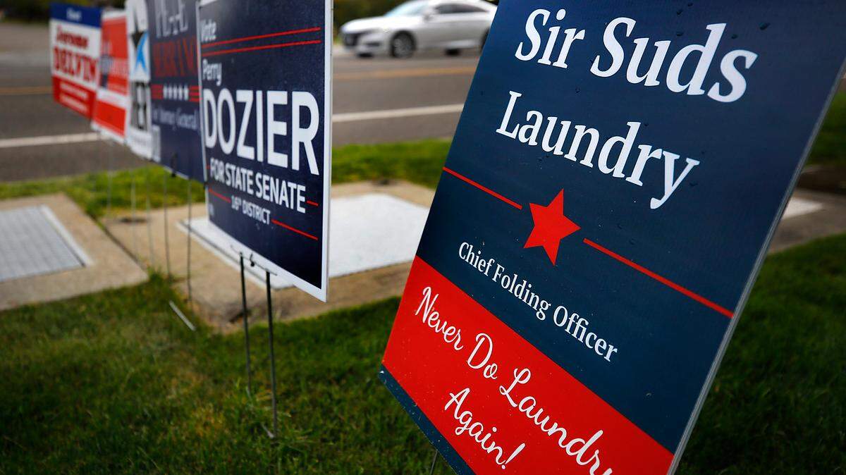 A satirical advertising sign for Sir Suds Laundry Co. in Richland has been placed adjacent to political signs on Columbia Point Drive in Richland.