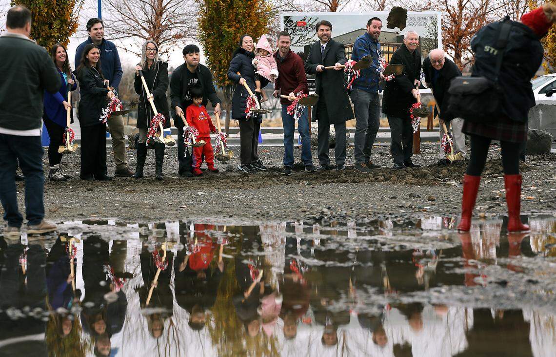 Isabelle Yuri Na holds her daughter, Ara, while standing next to her husband, Bumki Hong, and their son, Kai, during the soggy groundbreaking ceremony Friday with local officials for the first private-sector business to begin construction at Vista Field in Kennewick. They kicked off construction of the KUKI Izakaya Restaurant.