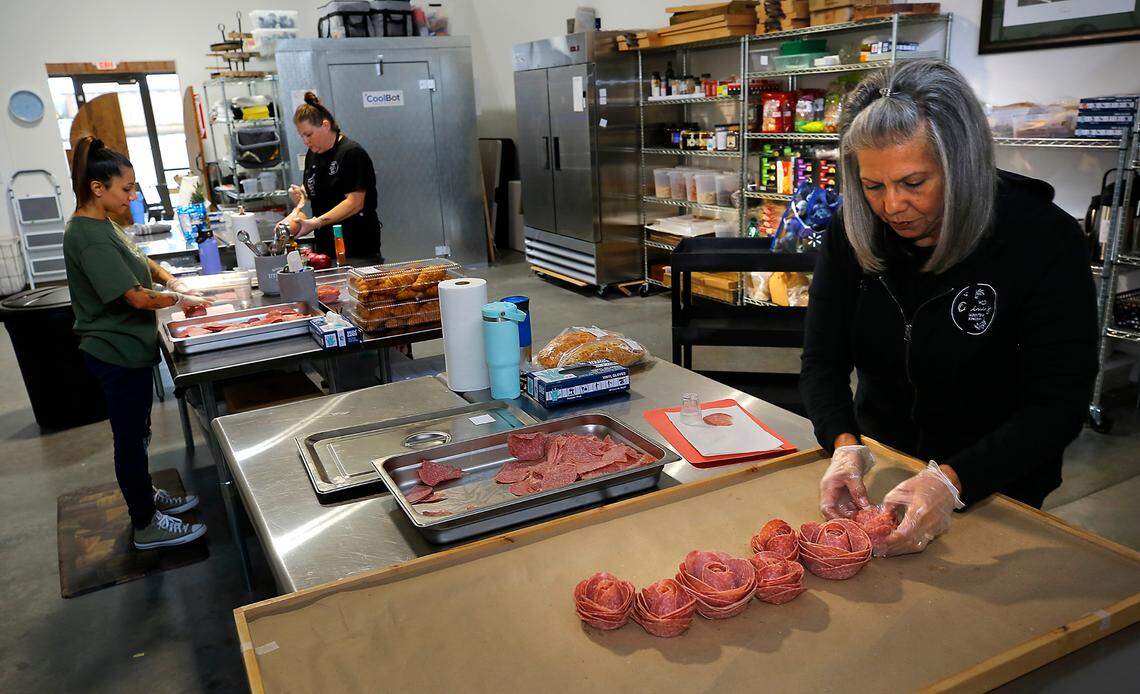 Jasmine Antonson, Jessi Schuh and Tina Beverly, from left work together building a large board order at the Wild Olive’s storement in Pasco.
