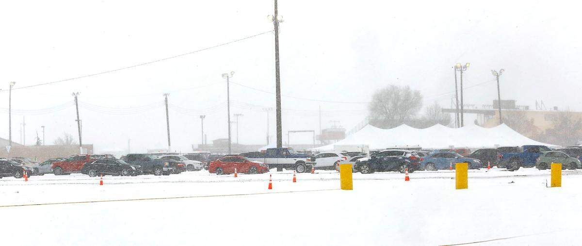 Snow continues falling Friday afternoon as people wait inside their cars in line to receive their COVID-19 vaccination at the drive-thru clinic set up in the parking lot of Benton County Fairgrounds. Anyone with an appointment for Saturday was being asked to come to the Benton County Fairgrounds on Friday in case the weather is worse on the weekend.