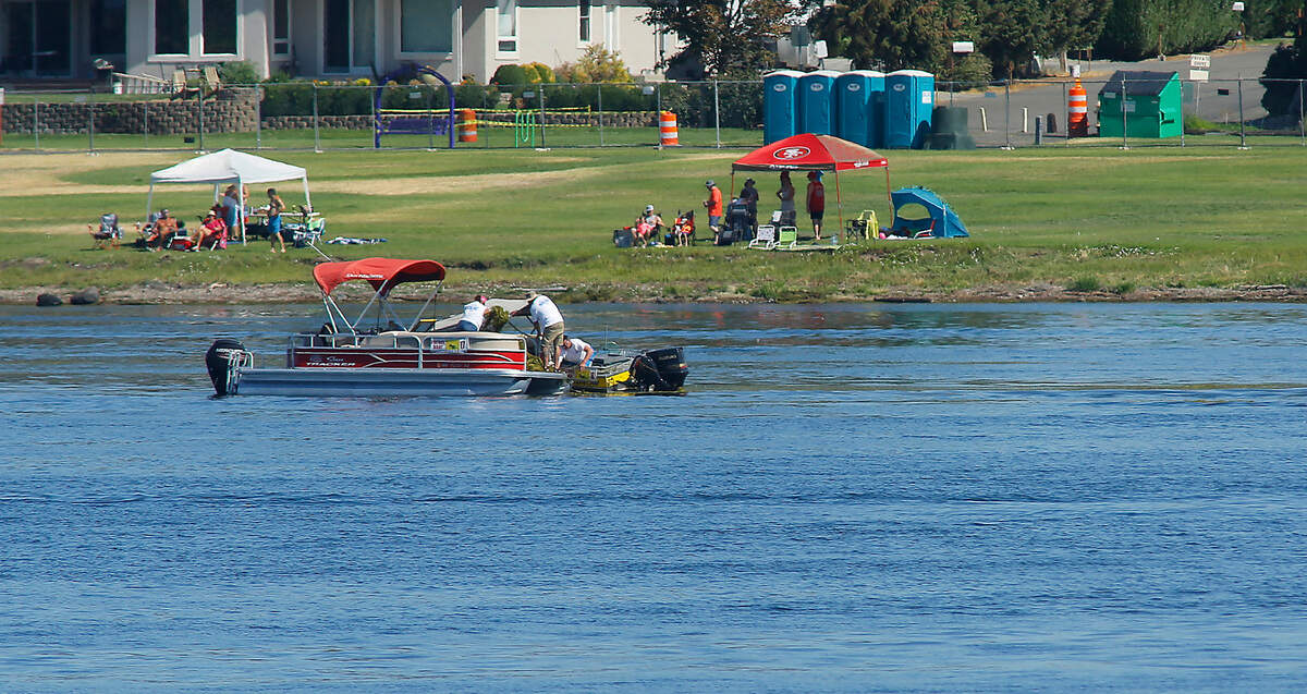 Water Follies volunteers in safety patrol boats load the front of pontoon boat with chunks of milfoil clogging the racing lanes on the Franklin County side of the Columbia River Friday morning.