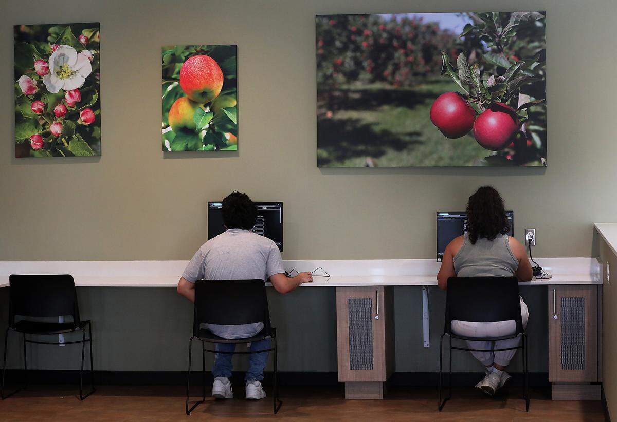 Residents at the Bishop Skylstad Commons work on computers in the lobby of the Pasco facility.