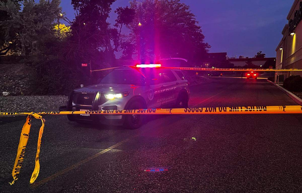 A Benton County Sheriff’s Office patrol vehicle is parked behind yellow police line tape near the HomeGoods store in Kennewick following an officer-involved shooting of a carjacking suspect.