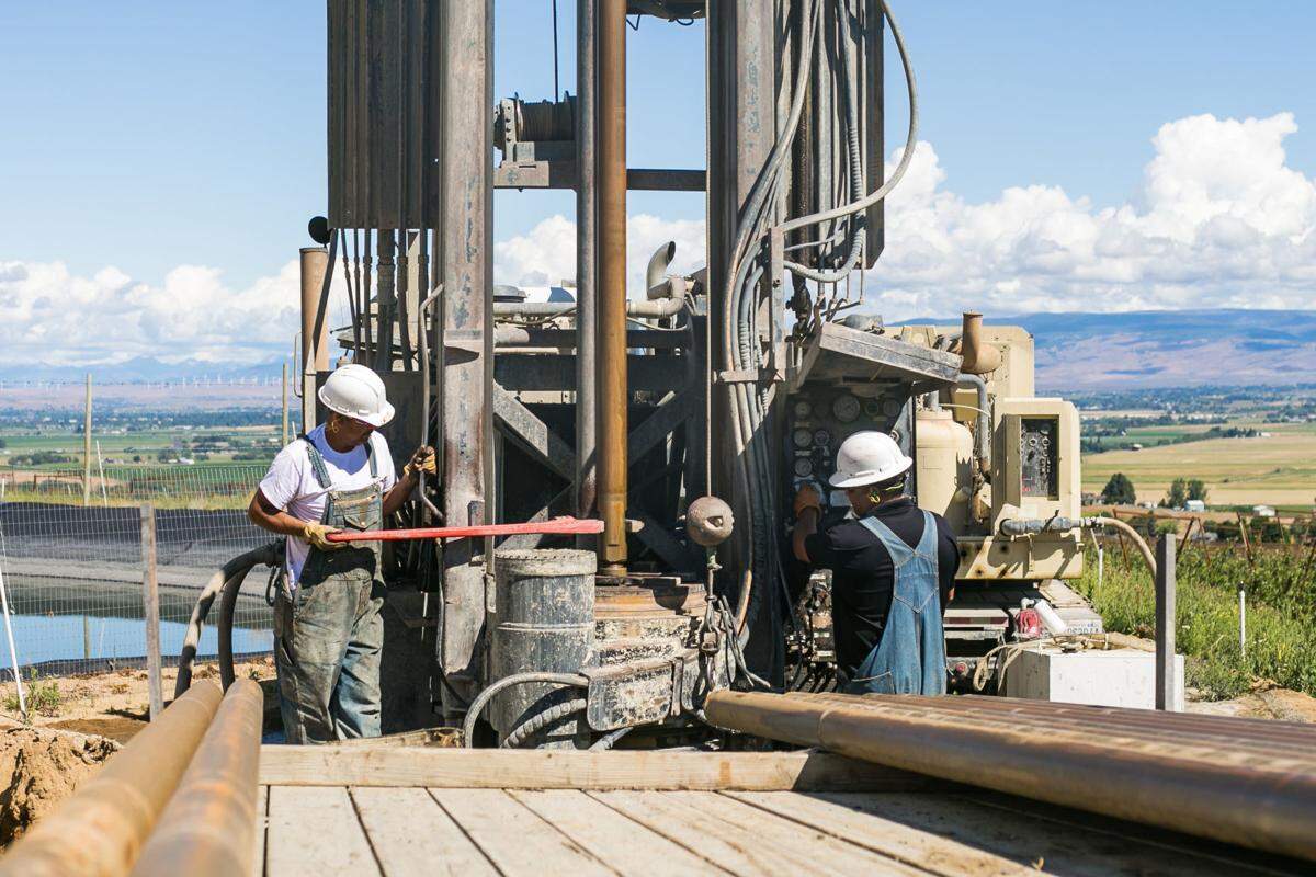 After days of drilling an emergency drought well for Zirkle Fruit Company, Victor Santillan, left, and Sal Valenciano of Bransen Drilling work on removing equipment from the wellbore in Ellensburg.